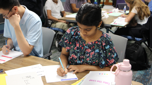 Student writting on paper at desk