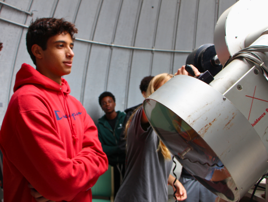 Student looking at observatory telescope