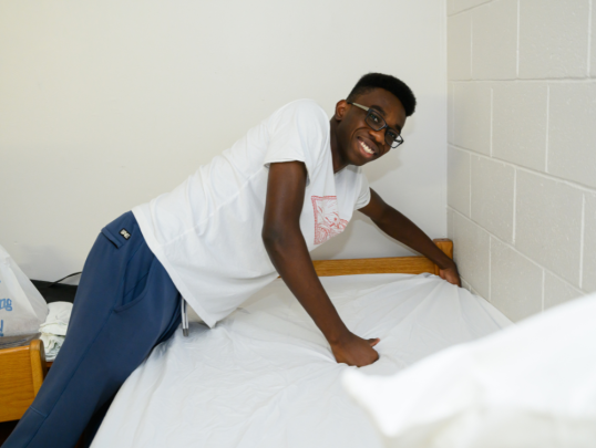 Student setting up bed in dorm during move in